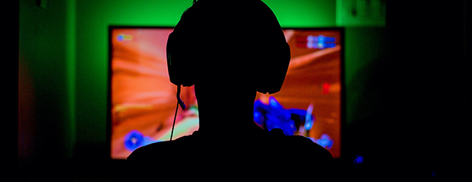 Ung person i siluett framför gamingskärm