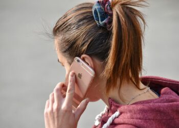 Kvinna snett bakifrån som pratar i mobil.